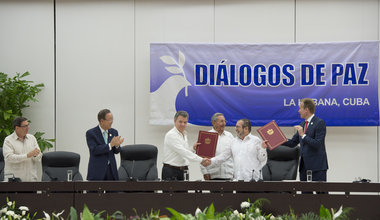 El presidente de Colombia, Juan Manuel Santos (segundo por la izq.), y el líder de las FARC-EP, Timoleón Jiménez, se dan la mano tras la firma del acuerdo sobre cese al fuego bilateral y definitivo, en presencia del Secretario General de la ONU, Ban Ki-moon (primero por la izq.). Foto: ONU/Eskinder Debebe